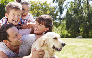Family relaxes outdoors with their dog after heeding HVAC tips for pet owners.