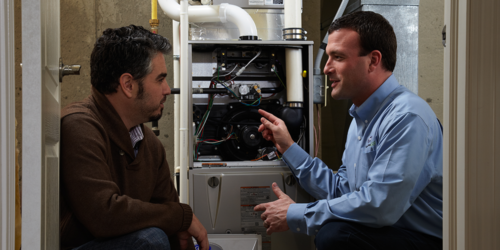 HVAC tech points out signs you need furnace repair to homeowner.