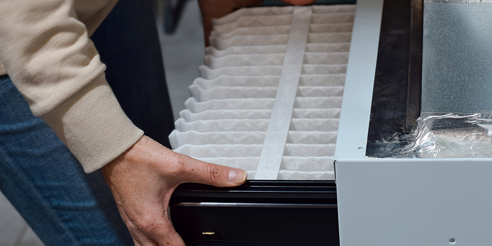 Person inserting an air filter into a heating unit.